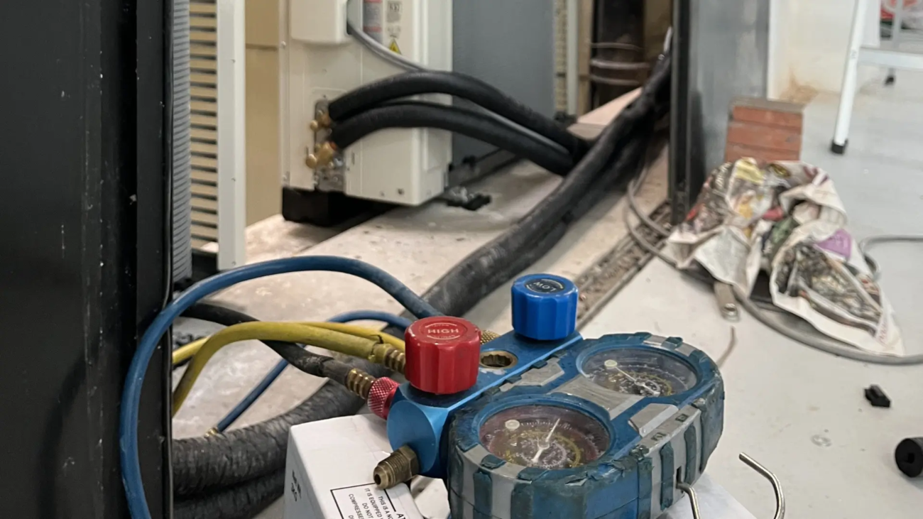 Decom Aircon technician performing aircon gas top up Singapore with manifold gauge on outdoor compressor