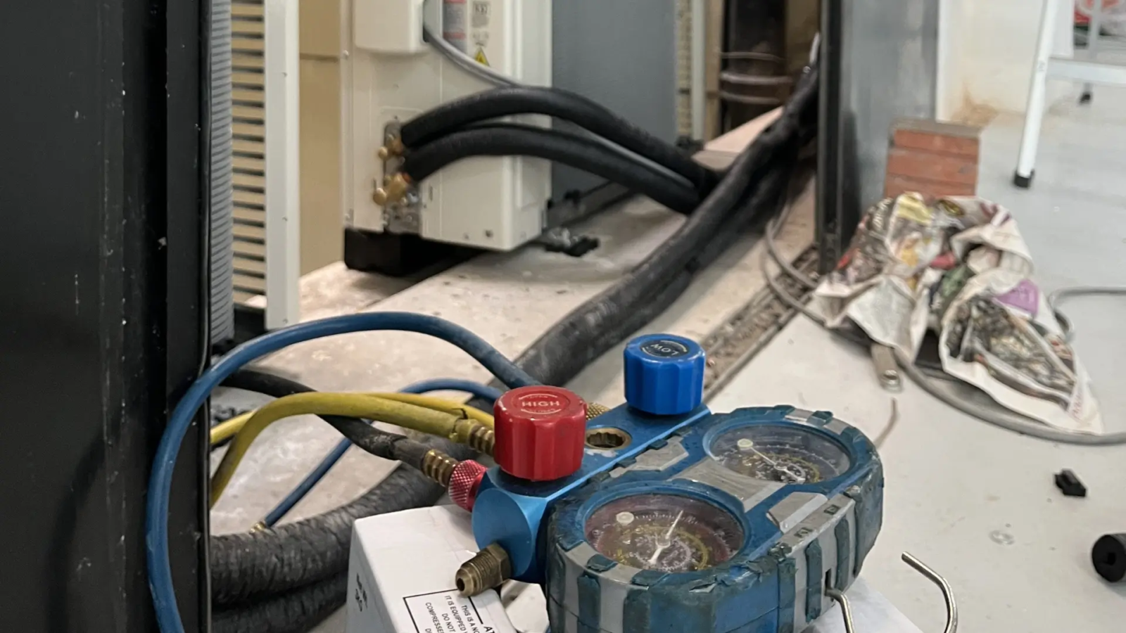 Decom Aircon technician performing aircon gas top up Singapore with manifold gauge on outdoor compressor