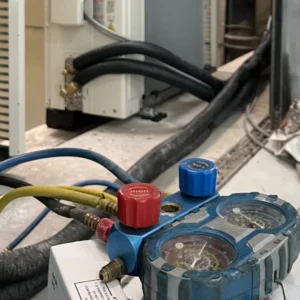 Decom Aircon technician performing aircon gas top up Singapore with manifold gauge on outdoor compressor