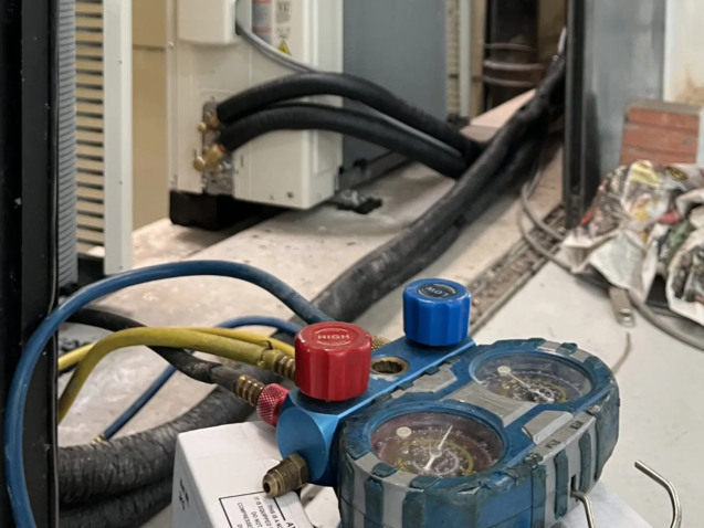 Decom Aircon technician performing aircon gas top up Singapore with manifold gauge on outdoor compressor