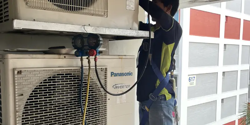 Aircon technician showing pressure gauge manifold reading to homeowner during refrigerant diagnostic check in Singapore home