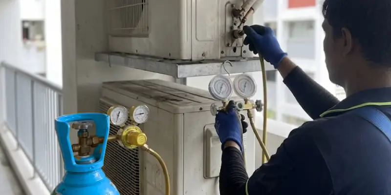 Aircon technician connecting nitrogen pressure test equipment to copper pipe service port on Singapore HDB flat outdoor unit for refrigerant leak detection