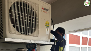 Technician inspecting air conditioner compressor inside outdoor unit Singapore HDB