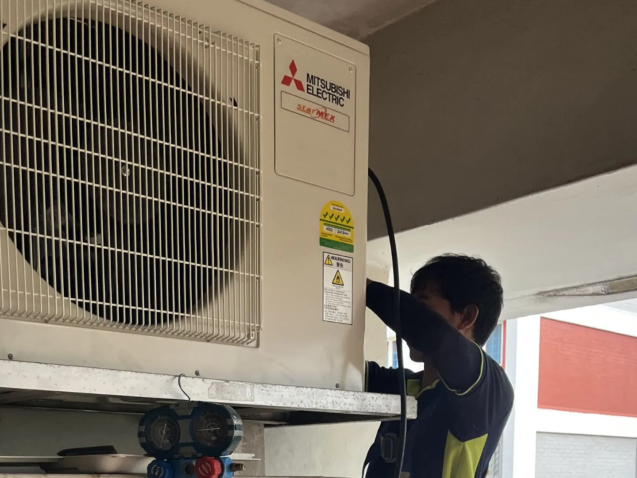 Technician inspecting air conditioner compressor inside outdoor unit Singapore HDB