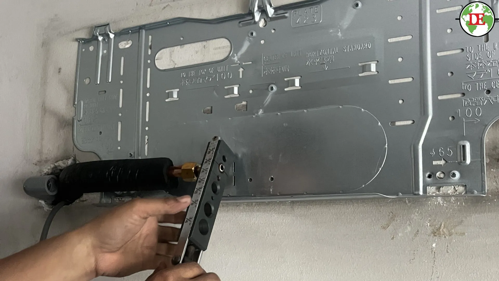 Technician measuring copper piping before relocating an air conditioner.