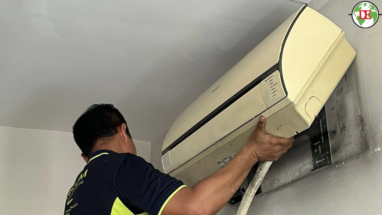 Professional technician relocating a split air conditioner inside a Singapore HDB flat.